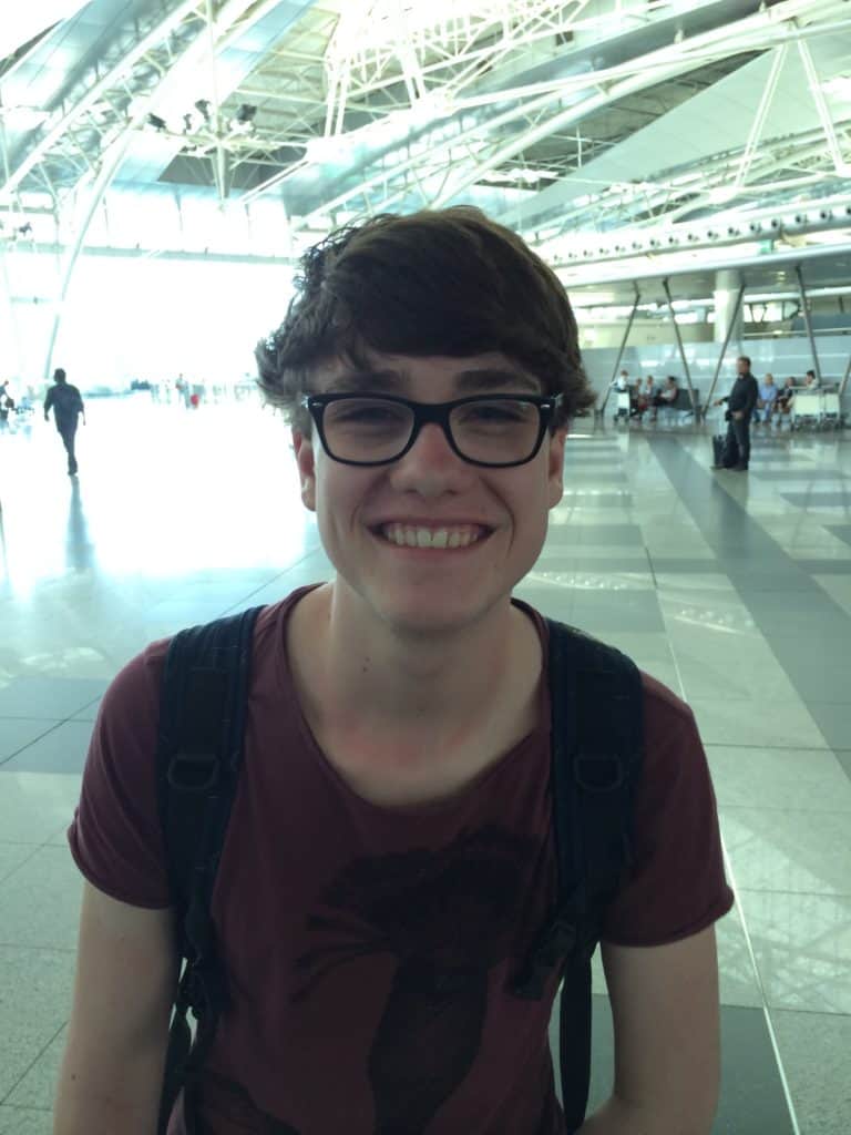 Travel picture of a guy in an airport hall smiling like he's high