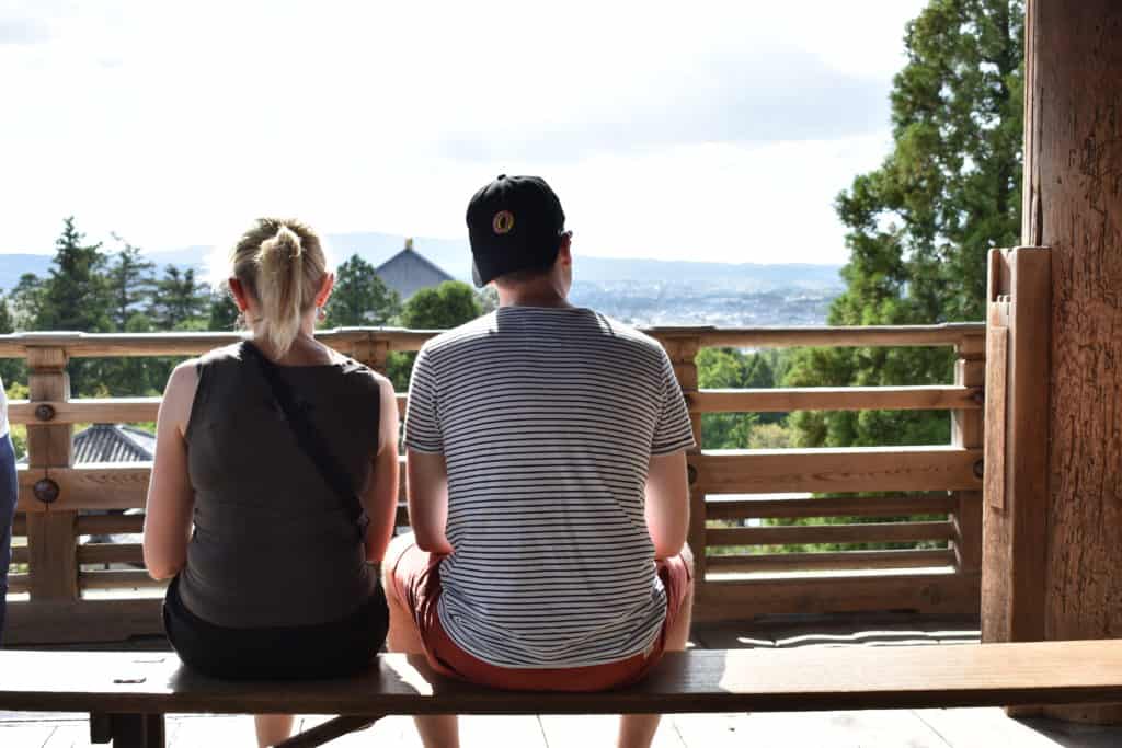 Mother and son sitting on bench, looking at view from Nigatsudo Hall (Nara)