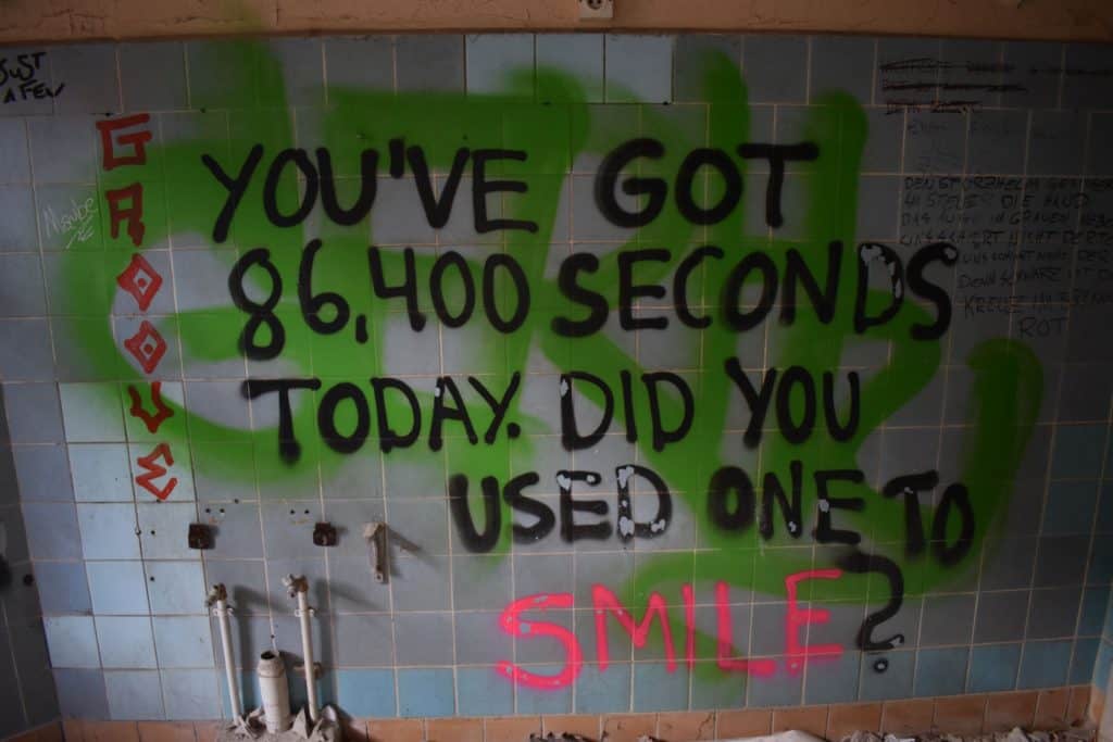One of the examples of thought-provoking graffiti art in this abandoned children's hospital ("You've got 86,400 seconds today. Did you use one to smile?"